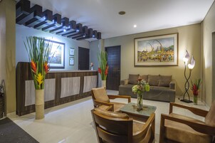 A modern lobby with a reception desk, seating area, and a painting on the wall.