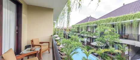 A balcony with a pool, lounge chairs, and hanging plants.