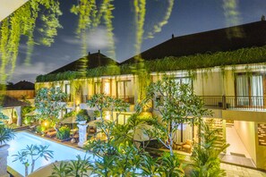 Un hotel con piscina, mobiliario exterior y abundante vegetación.