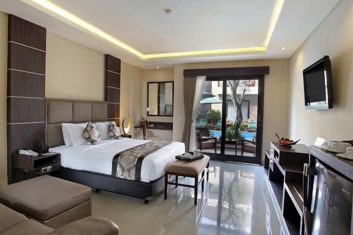 A modern hotel room with a large bed, a desk, a television, and a view of the outdoors.
