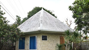 A stone house with a peaked roof, a small window, and a door. - King Arthur's Place (Alcoy)