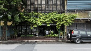 A building with a modern facade, featuring vertical wooden slats and a prominent sign with Chinese characters. - Chingcha Bangkok - Hostel (Bangkok)