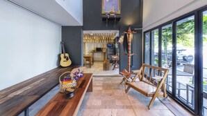 A spacious interior with a wooden bench, a guitar, and a table with a basket and flowers. - Chingcha Bangkok - Hostel (Bangkok)