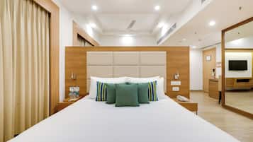 Een hotelkamer met een groot bed, een houten hoofdeinde, een nachtkastje met een telefoon en een spiegel.