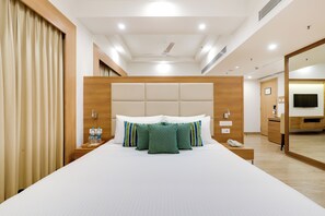 Habitación de hotel con una cama grande, cabecera de madera, mesita de noche con un teléfono y un espejo.