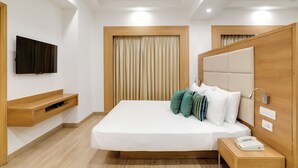 A modern hotel room with a bed, a TV, a bedside table with a phone, and a ceiling fan. - Lemon Tree Hotel, Sector 60, Gurugram (Sohna)