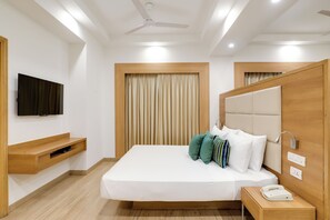 A modern hotel room with a bed, a TV, a bedside table with a phone, and a ceiling fan. - Lemon Tree Hotel, Sector 60, Gurugram (Sohna)