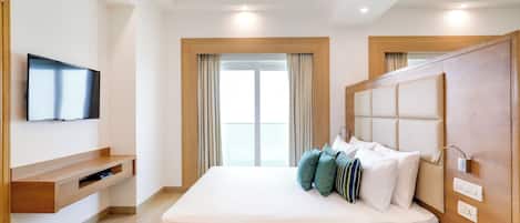 A modern hotel room with a bed, a television, a bedside telephone, and a wooden headboard.