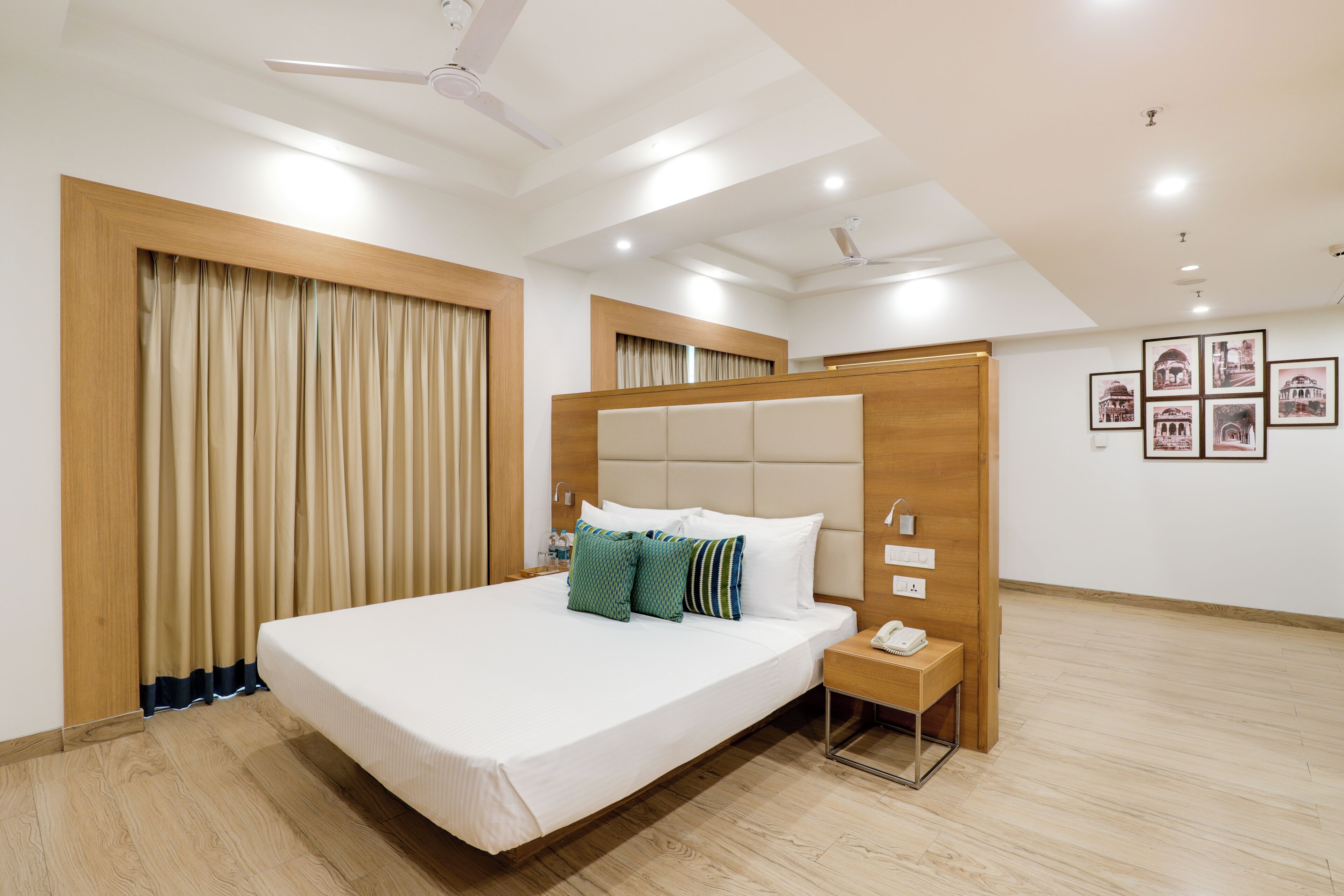 Una habitación de hotel moderna con una cama grande, una mesita de noche, un teléfono y un ventilador de techo.