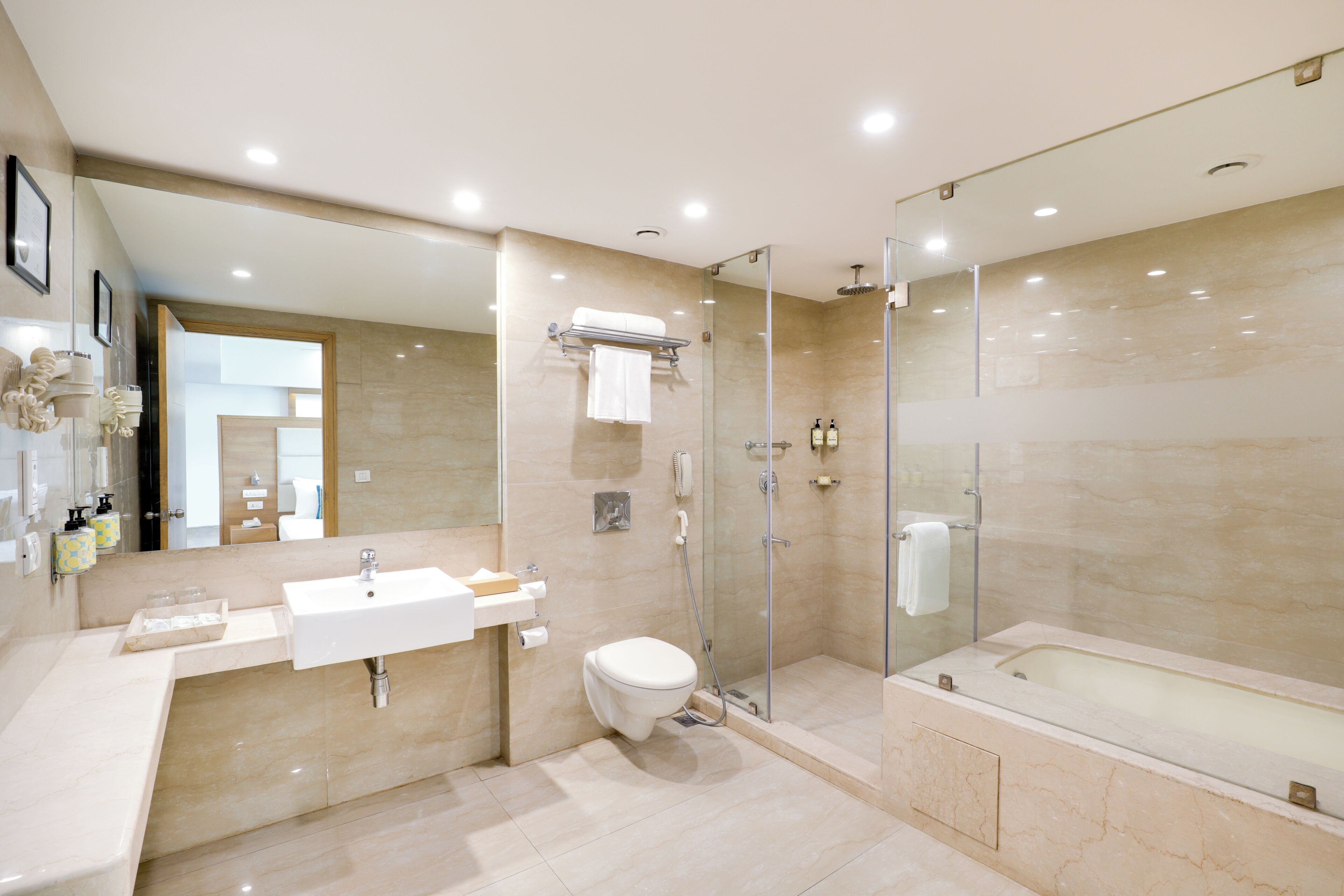 Un baño moderno con ducha envuelta en vidrio, una bañera independiente y un lavabo con espejo.