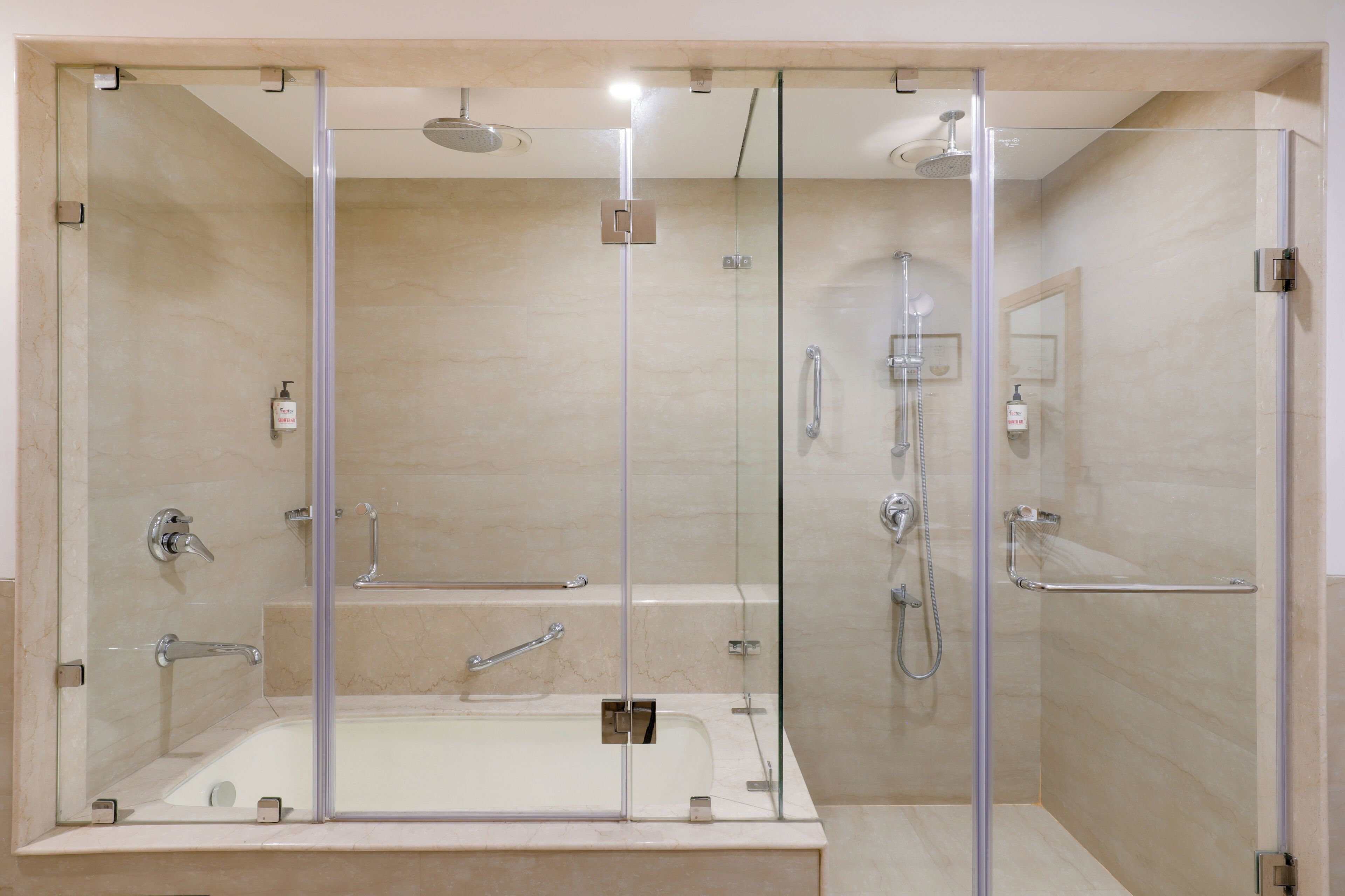 Zona de ducha con mampara de vidrio y bañera, puerta de ducha de cristal y barra de apoyo.