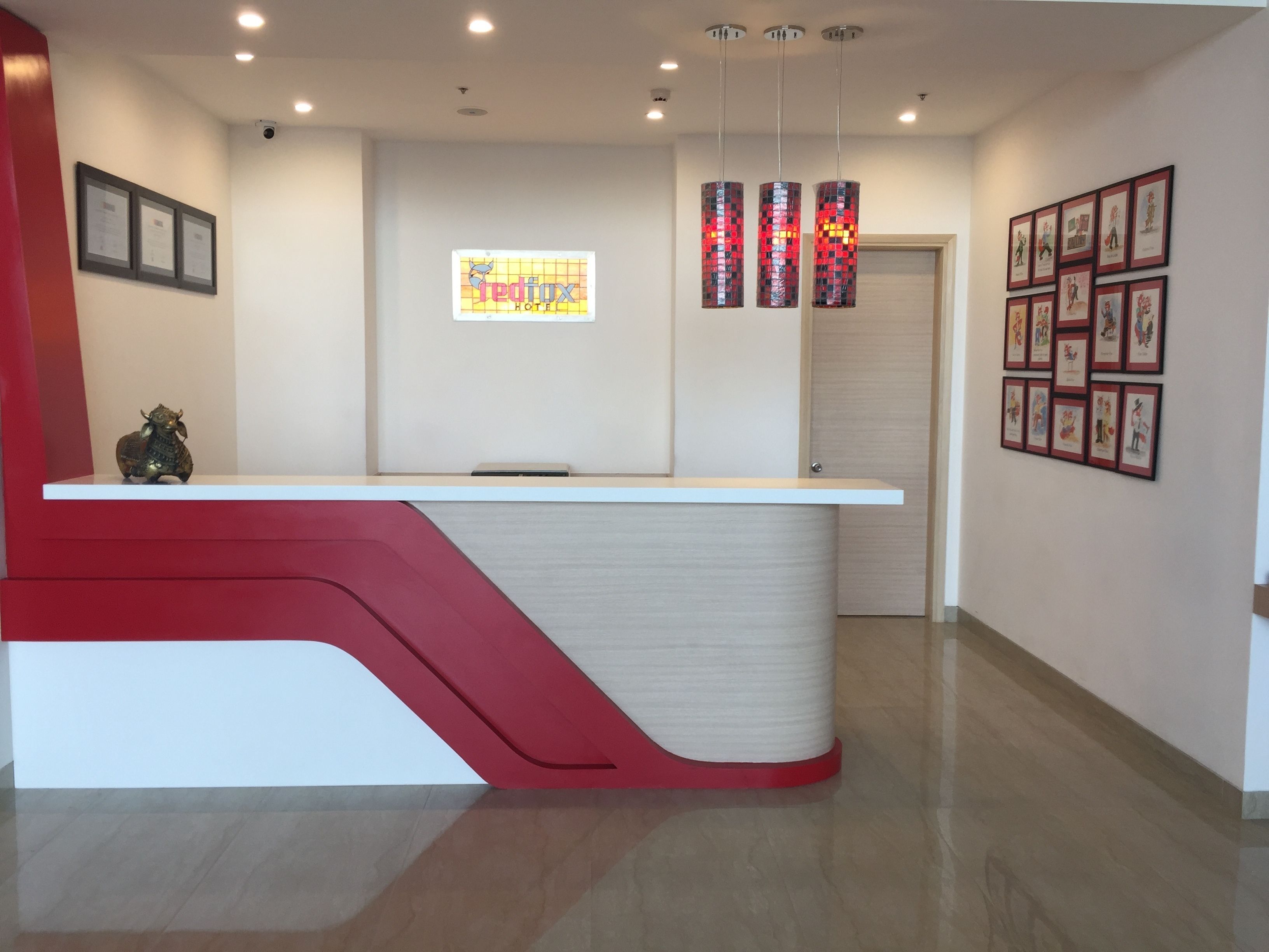 A reception desk with a modern design, a framed sign above it, and a series of framed pictures on the wall to the right.