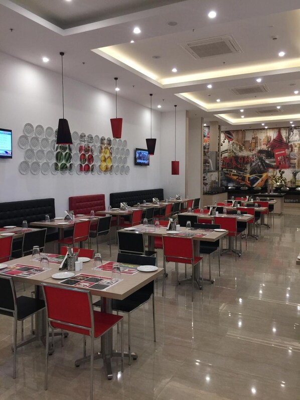 A restaurant with multiple tables and chairs, a wall-mounted TV, and a ceiling with recessed lighting. - Red Fox by Lemon Tree Hotels, Sector 60, Gurugram (Sohna)