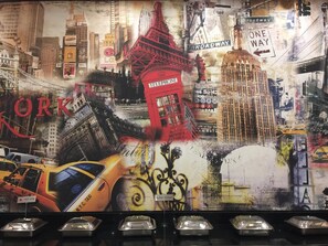 A wall with a collage of city landmarks and signs, including a red telephone booth and a yellow taxi. - Red Fox by Lemon Tree Hotels, Sector 60, Gurugram (Sohna)