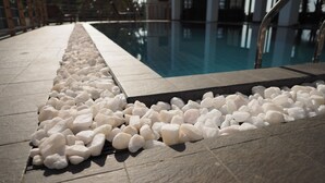 A pool area with white pebbles and a tiled walkway. - The Seascape (Matara)
