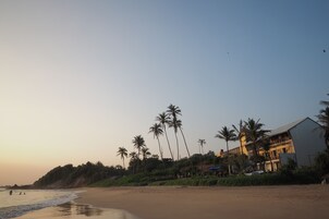 Una playa con palmeras y un edificio de varios balcones.