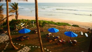 A beachside lounge area with sun loungers and blue umbrellas, overlooking the ocean. - The Seascape (Matara)