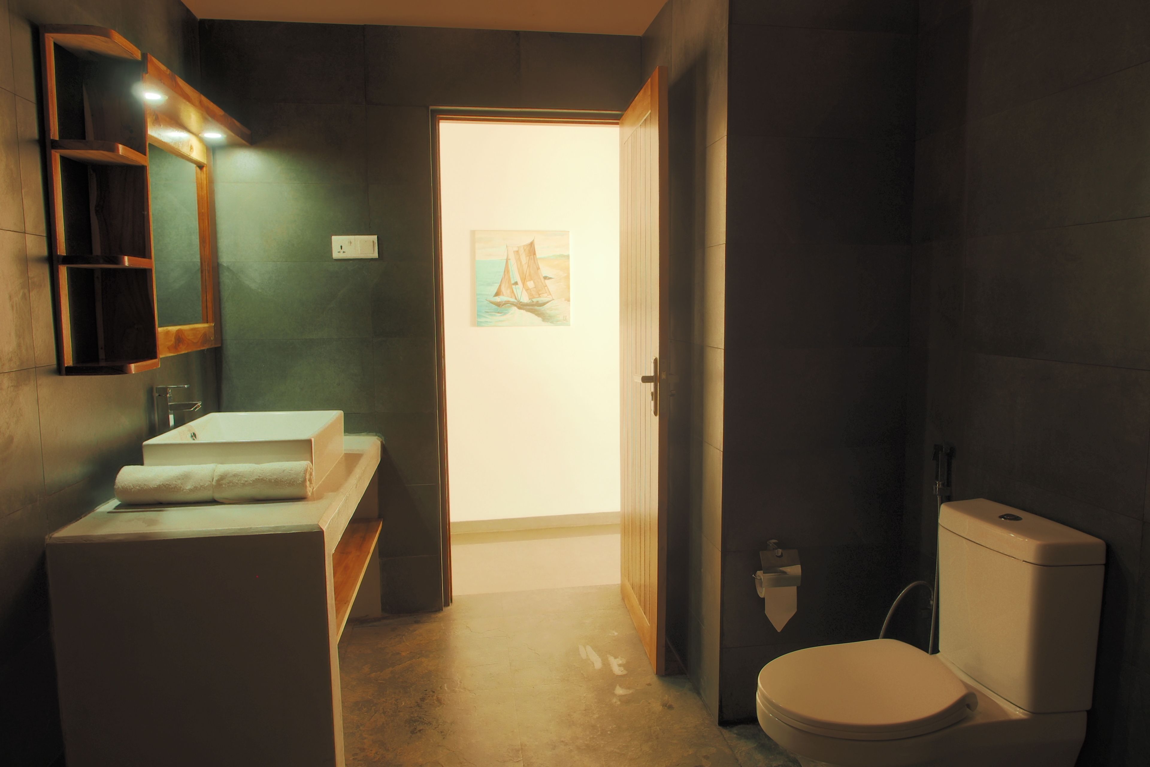 Un baño moderno con lavamanos, espejo e inodoro.