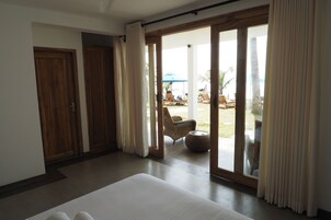 A hotel room with a large bed, sliding glass doors leading to an outdoor seating area with chairs and a table.