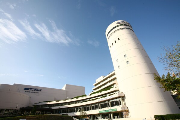 A modern hotel with a cylindrical tower, multiple floors, and a sign indicating it is the Fukuoka Sun Palace Hotel.