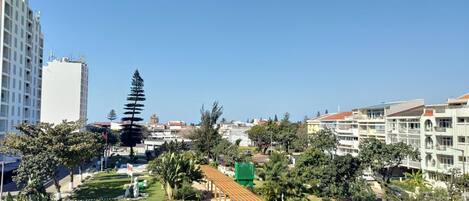 A residential area with modern buildings, a well-maintained garden, and a clear blue sky.