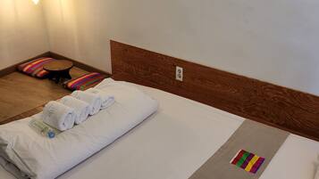 Una cama bien hecha con sábanas blancas, un cabecero de madera y un colorido tapete a rayas en el suelo.
