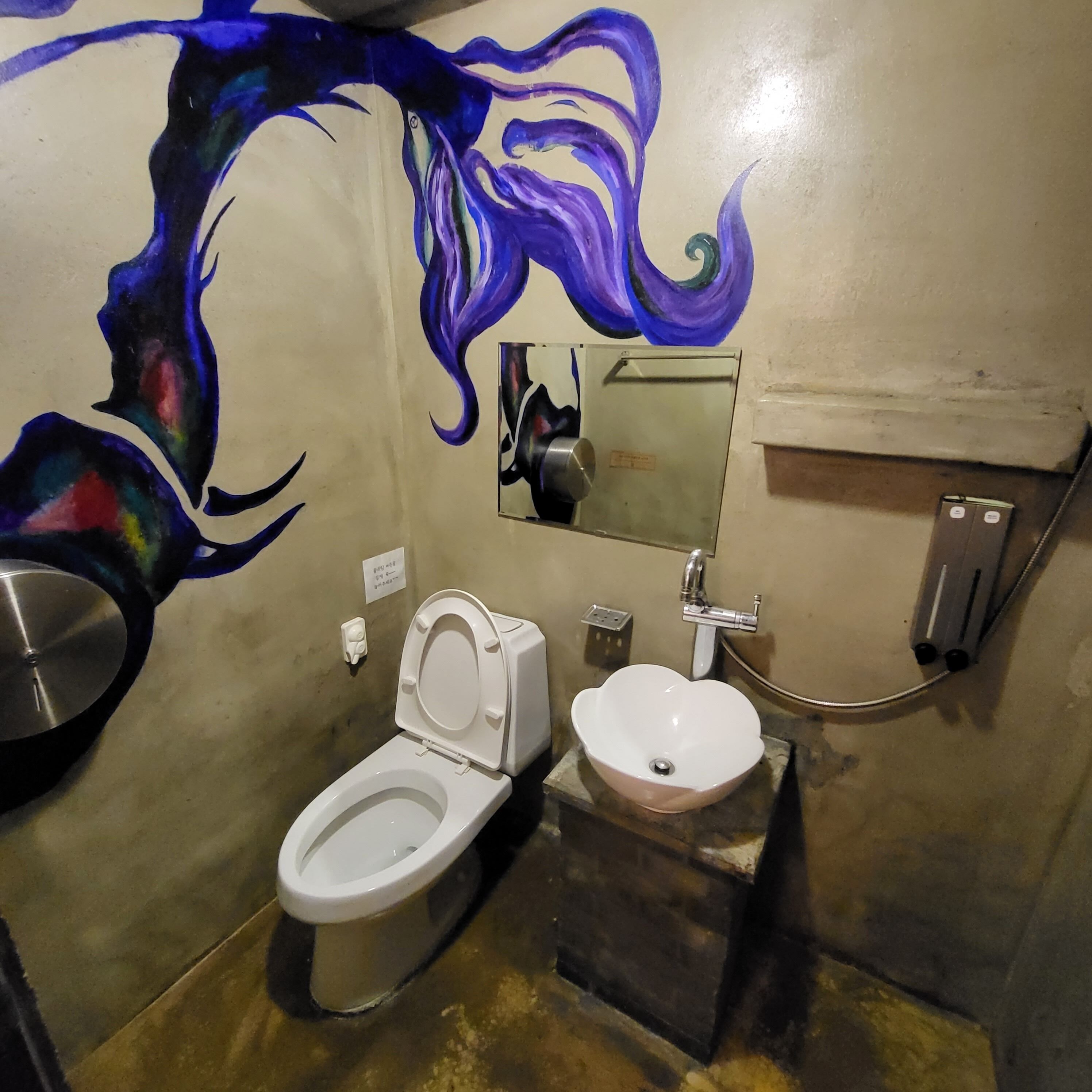 A bathroom with a white toilet, a sink, and a mirror.