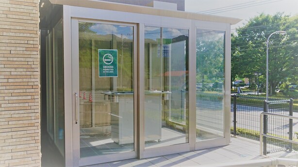 Een modern gebouw met een glazen ingang en een bord dat roken toestaat.
