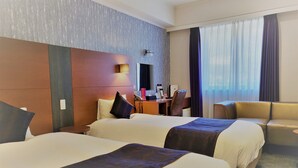 Een hotelkamer met twee bedden, een bureau, een stoel en een bank.