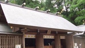 Een traditioneel Japans gebouw met een betegeld dak, houten pilaren en een kleine tafel buiten.