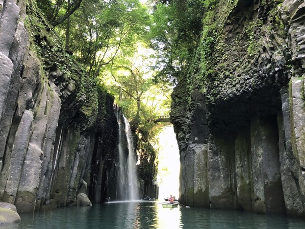 Una cascada en una cueva de paredes de piedra con un bote en el agua.