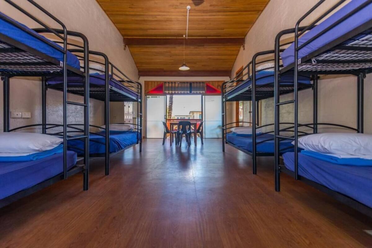 Un dormitorio con literas, suelo de madera y una mesa central.