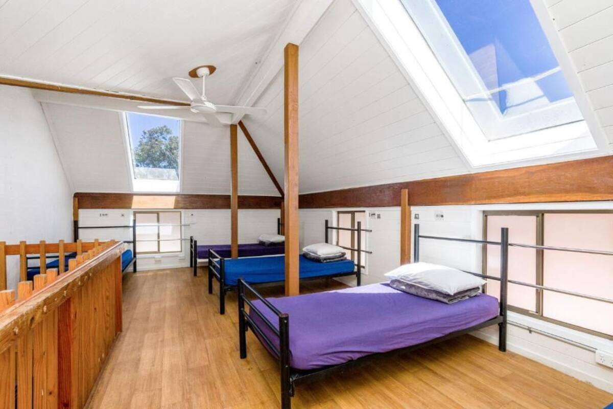 Un dormitorio con literas, ventilador de techo y tragaluces.