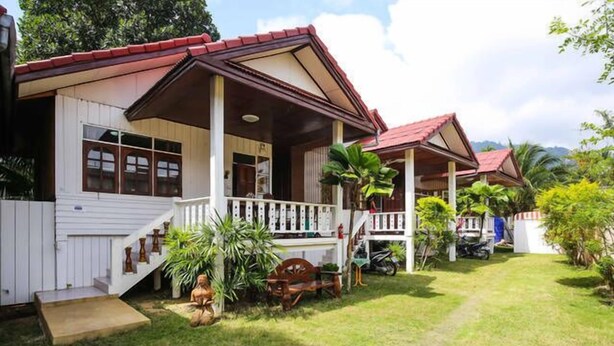 A two-story house with a porch, a small garden, and a pathway leading to the entrance. - Happy House (Koh Samui)