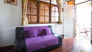 A room with a purple sofa, wooden windows, and a sliding glass door leading outside. - Happy House (Koh Samui)