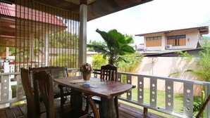 An outdoor wooden deck with a table and chairs, surrounded by a metal railing. - Happy House (Koh Samui)
