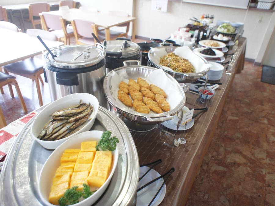 Une table de buffet proposant divers plats, notamment du poisson, du fromage et d’autres aliments préparés.