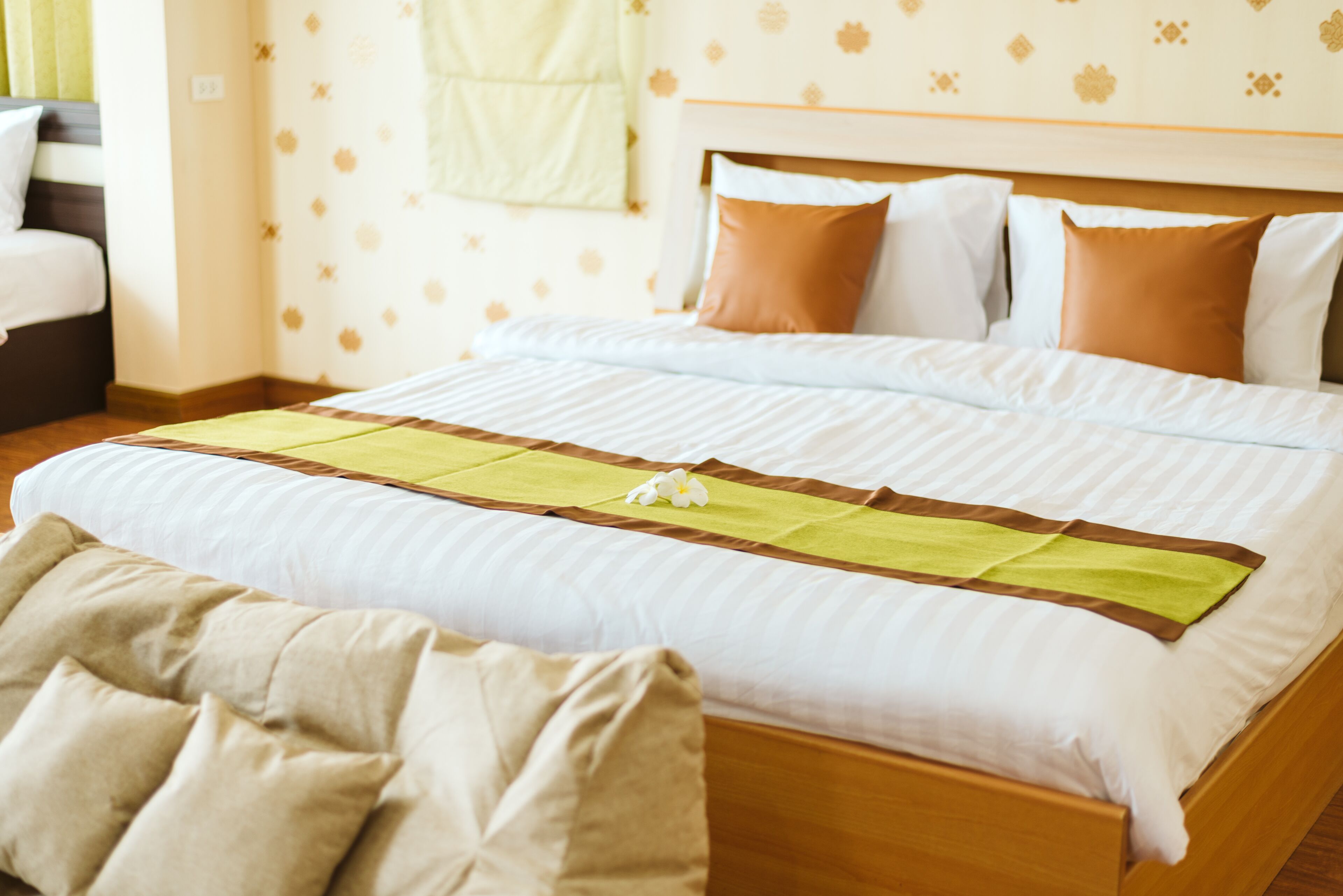 A neatly made bed with a striped bedspread, a green and brown runner, and multiple pillows.