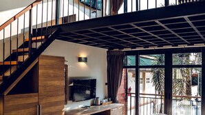 A modern bedroom with a large bed, a wooden wardrobe, a desk with a flat-screen TV, and a staircase leading to an upper level. - 15 Palms Beach Resort (Ko Chang)