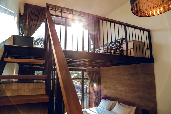 Un dormitorio con cabecera de madera, cama con ropa de cama blanca y una escalera que conduce a un nivel superior.