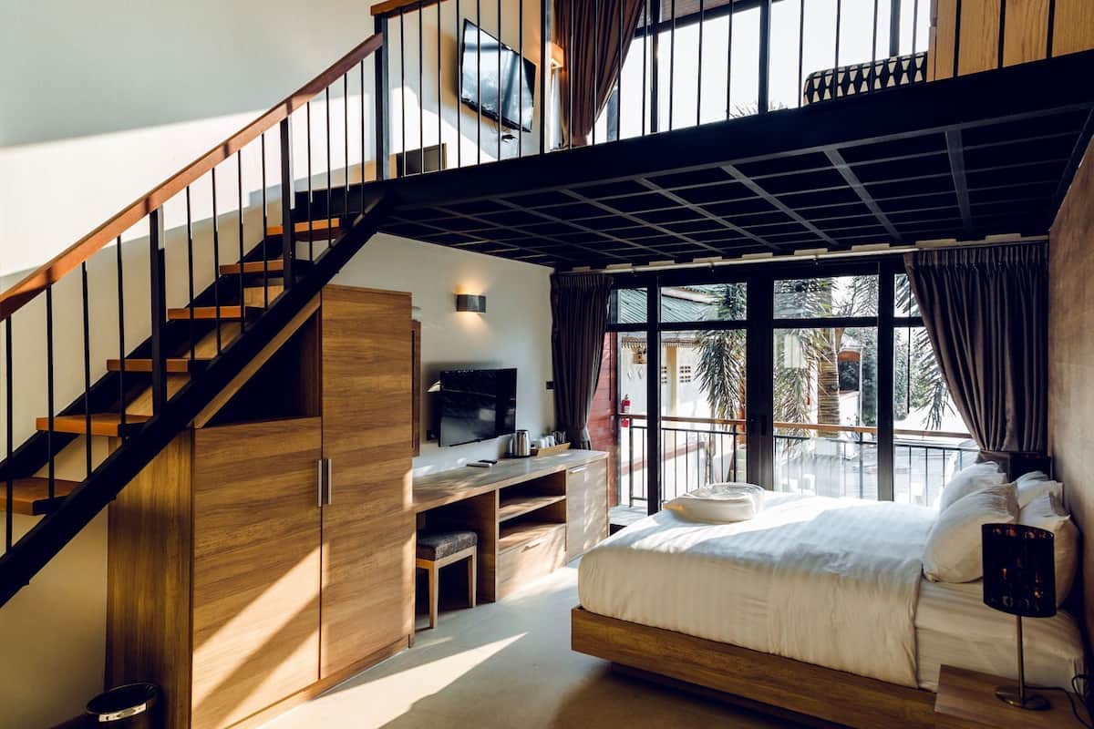 A bedroom with a bed, a desk, a TV, and a staircase.