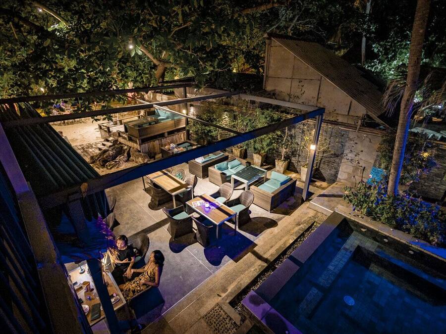 Un área de piscina al aire libre con sillones de descanso y un porche cubierto.