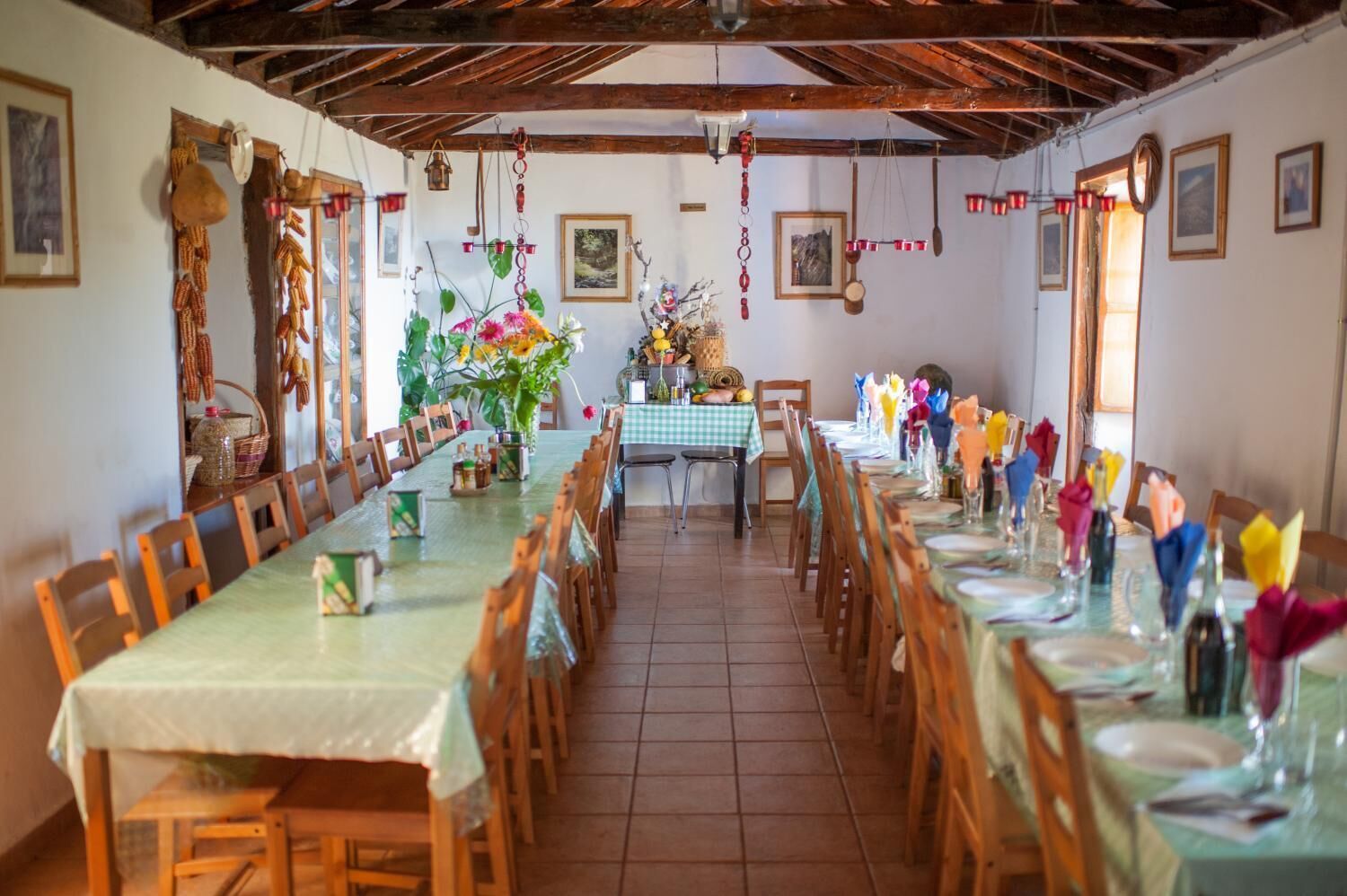 A dining area with long tables, wooden chairs, and a rustic ceiling.