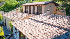 Una villa con techo de tejas de arcilla, pared de piedra y zona de patio con mobiliario exterior.