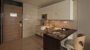 Een moderne keuken met een magnetron, spoelbak en houten stoelen.