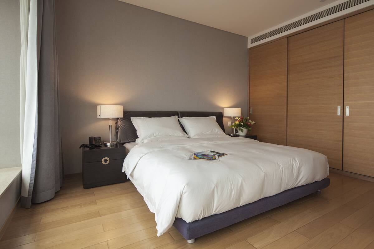 Une chambre à coucher moderne avec un grand lit, des lampes de chevet, une table de chevet et une armoire.