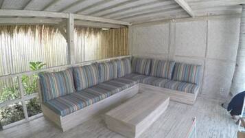 A covered outdoor seating area with a wooden bench and a cushioned sofa.