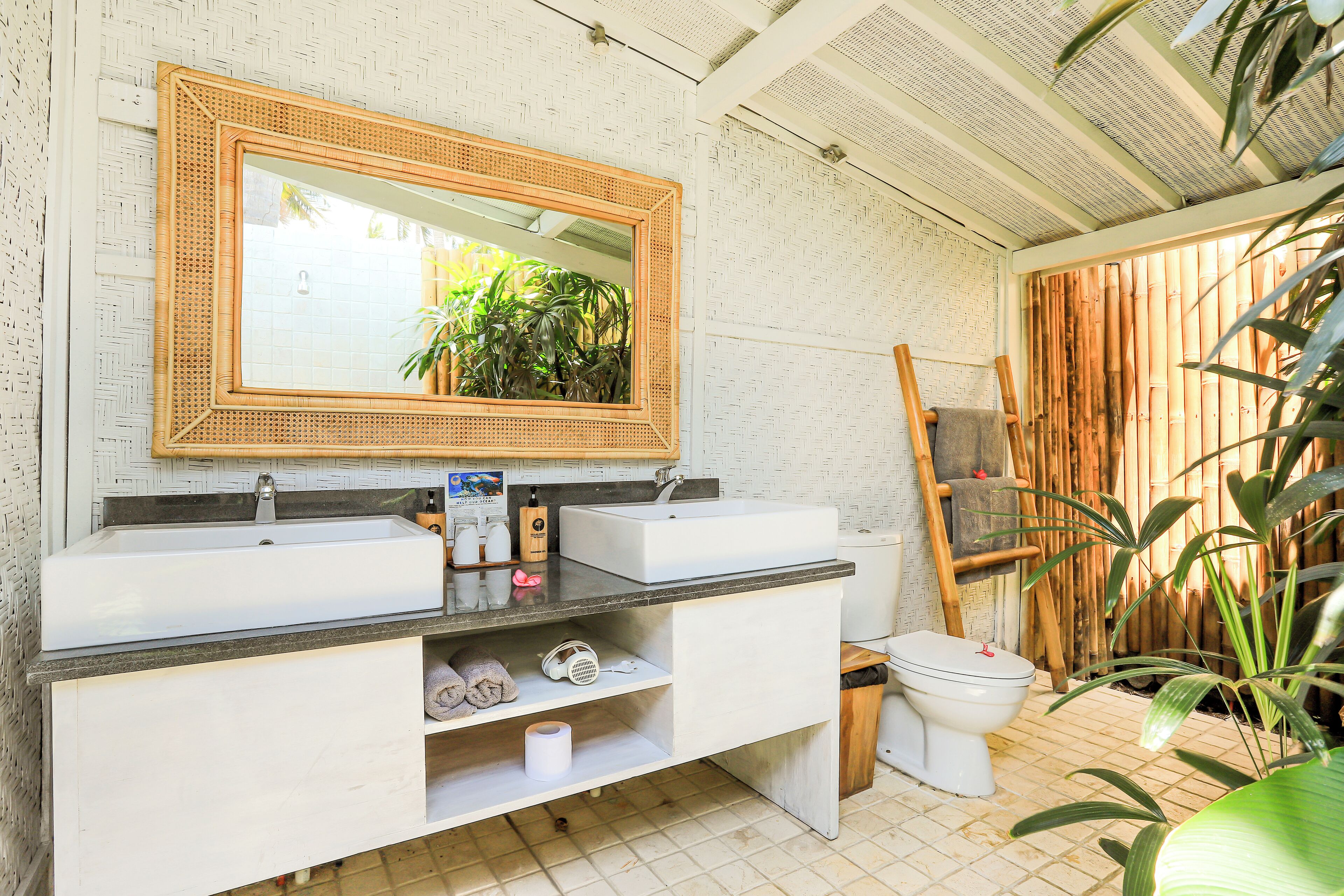 Un baño con dos lavamanos, un espejo grande, inodoro y zona de ducha.