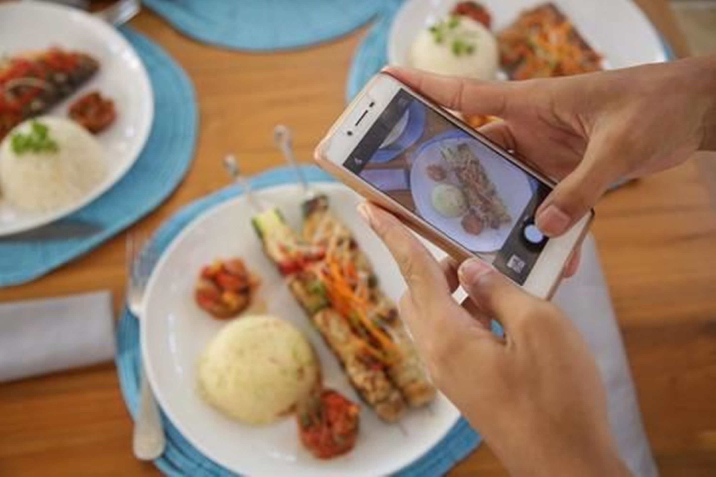 Una persona fotografiando un plato con un teléfono inteligente.