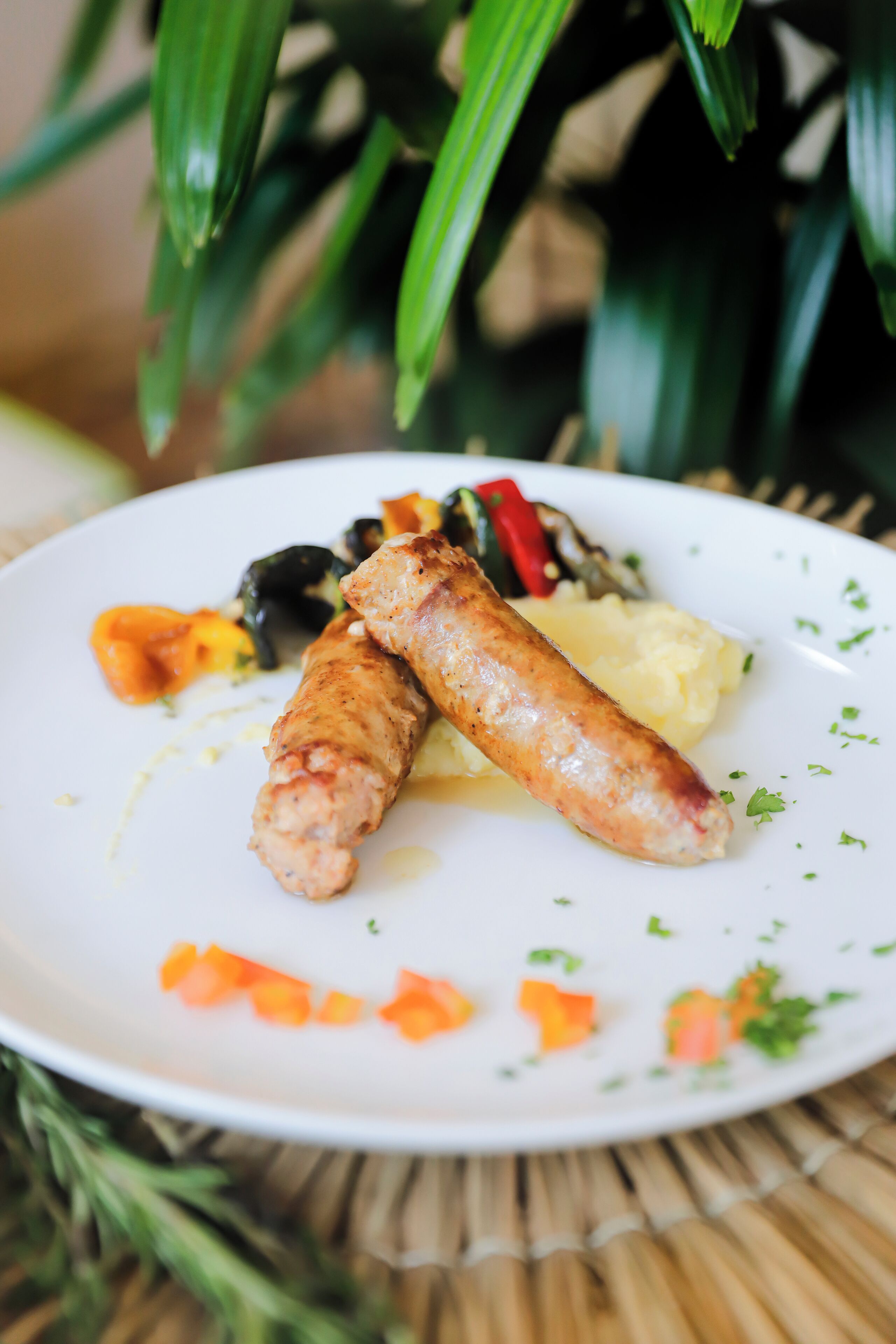 Une assiette contenant des saucisses, de la purée de pommes de terre et des légumes.